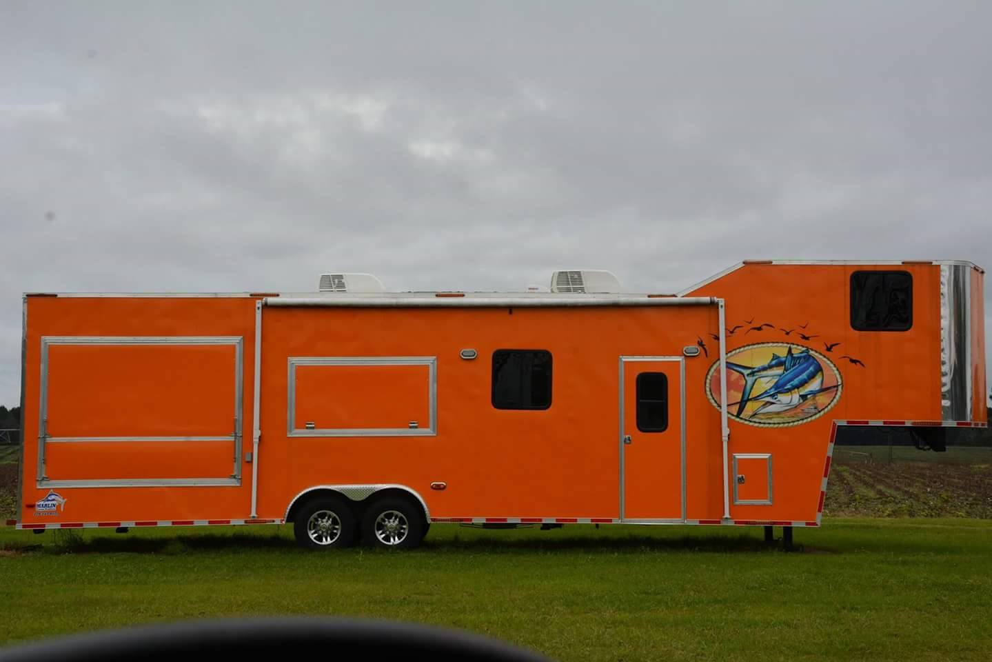 The image shows a bright orange and white recreational vehicle  RV  parked on grass, with visible branding and a logo that includes an airplane.
