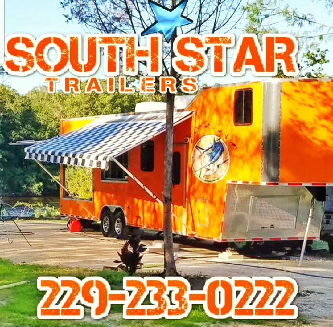 The image is a photograph of a large, orange camper trailer parked on an asphalt surface. It features a logo and text that reads  SOUTH STAR TRAILERS  with a phone number beneath it. The background suggests the photo was taken outdoors during daylight hours.